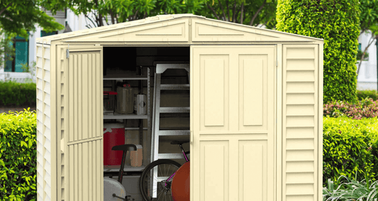 Duramax shed with open doors showcasing organized storage for bikes and garden tools in a landscaped backyard.