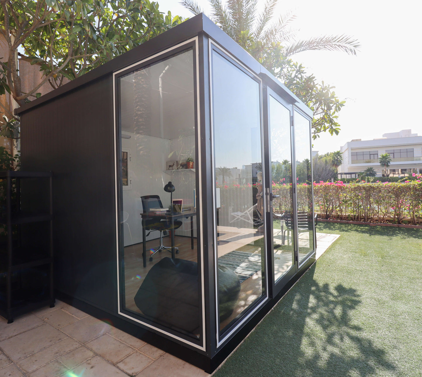 Duramax 10x10 Glass Garden Room set in a backyard, showcasing steel walls, clear glass panels, and a modern design for versatile use.