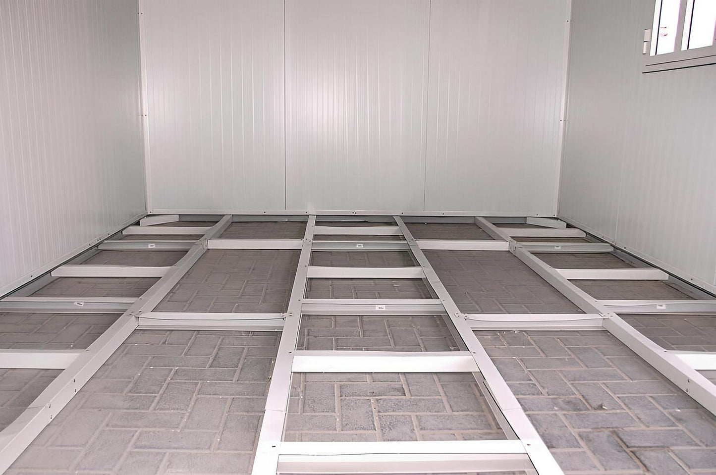 Interior of Duramax 19x10 Flat Roof Insulated Building showcasing durable galvanized steel framework and brick floor.