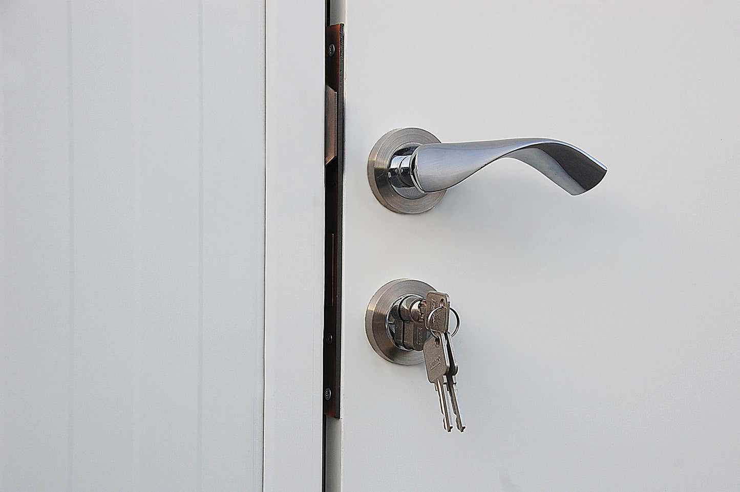 Close-up of a metal door handle with a key inserted in the lock, highlighting security and access features.