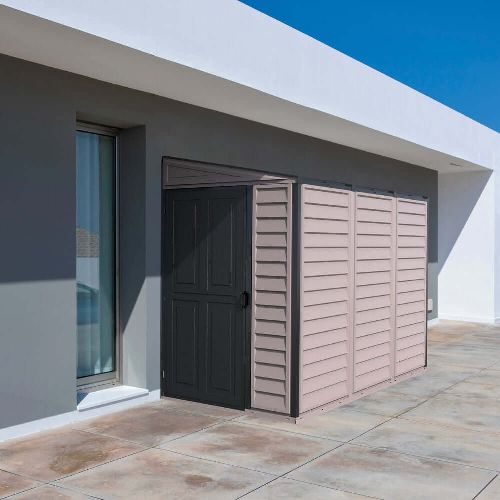 Duramax 4x8 SideMate PLUS Vinyl Shed in Grey near house, ideal outdoor storage solution; sleek design fits home aesthetics.