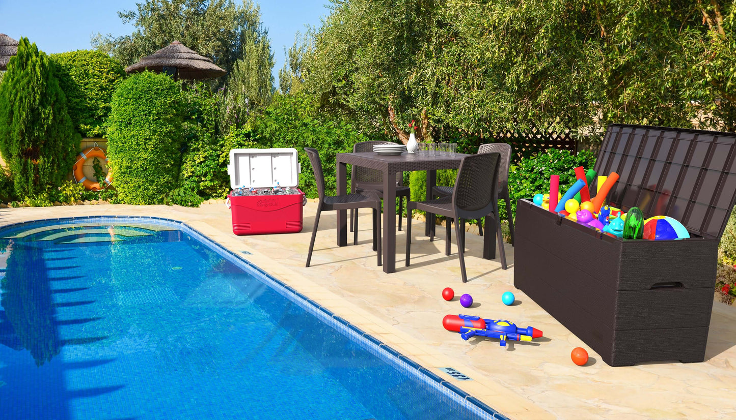 Outdoor scene with a Duramax 71 Gallon Deck Box storing pool toys beside a glass table and chairs near a swimming pool.