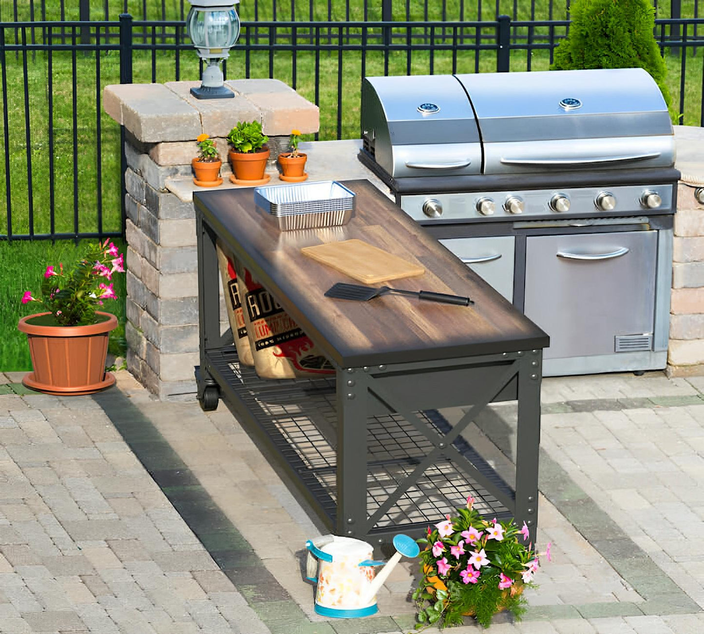 Outdoor setup with Duramax rolling workbench and stainless steel grill, surrounded by potted plants on a paved patio.