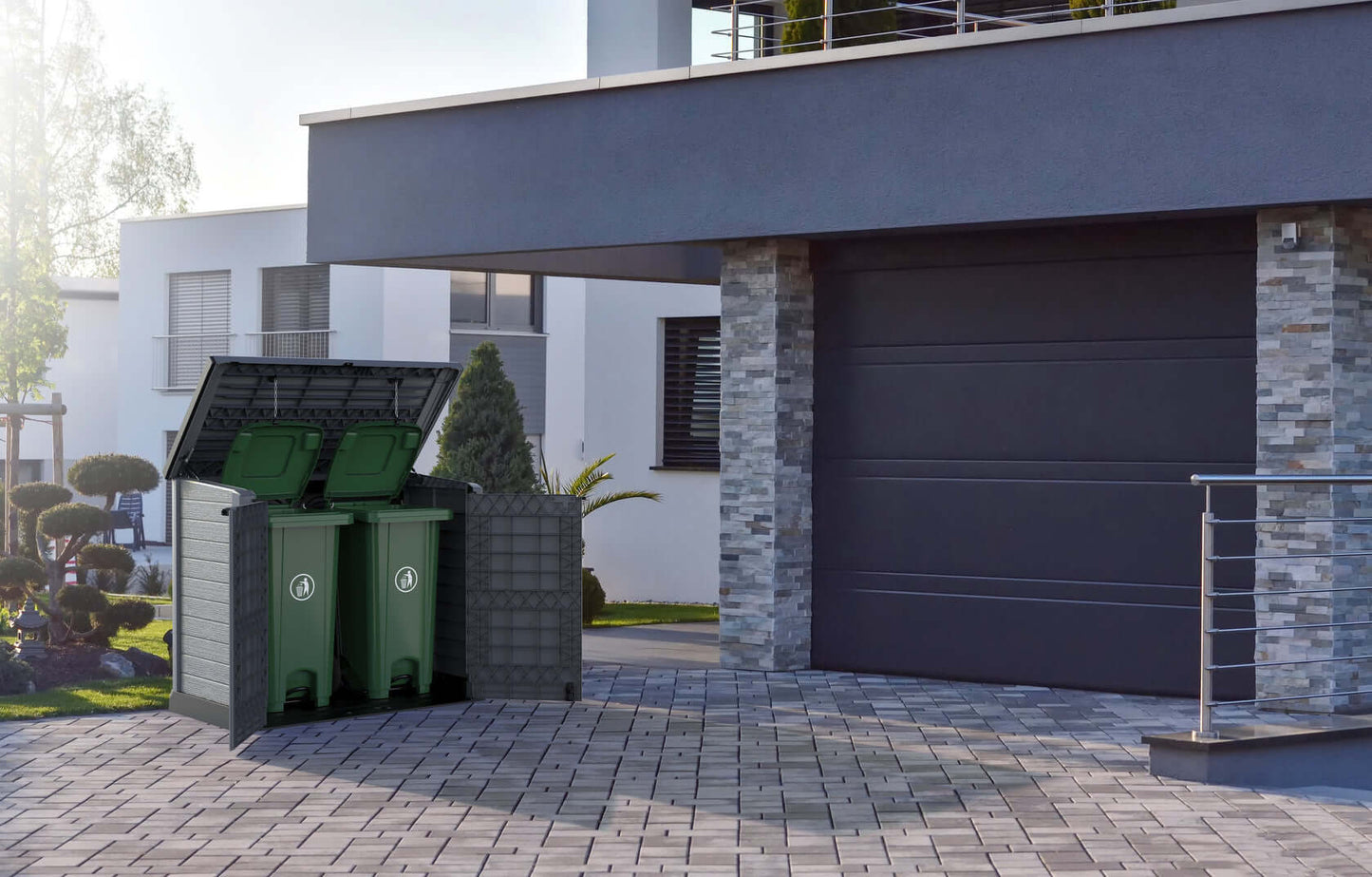 Duramax Storeaway garden shed with flat lid open, housing two green bins, placed on modern driveway; ideal outdoor storage solution.