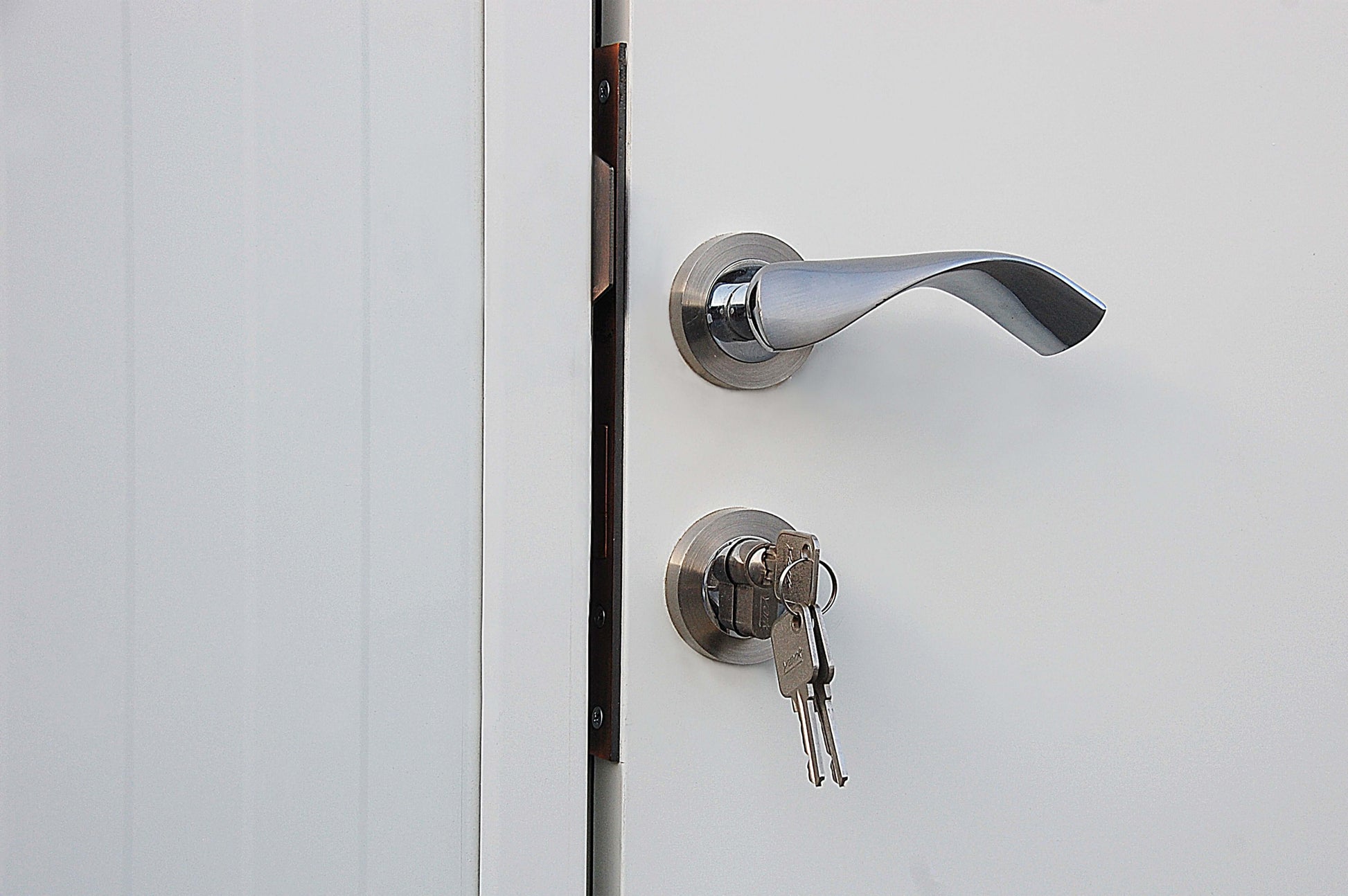 Close-up of a modern door handle and lock with keys in an insulated building.