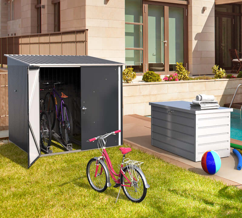 Duramax 6x6 bike shed with open doors showing bicycles inside, set on a grassy area beside a pool and house.