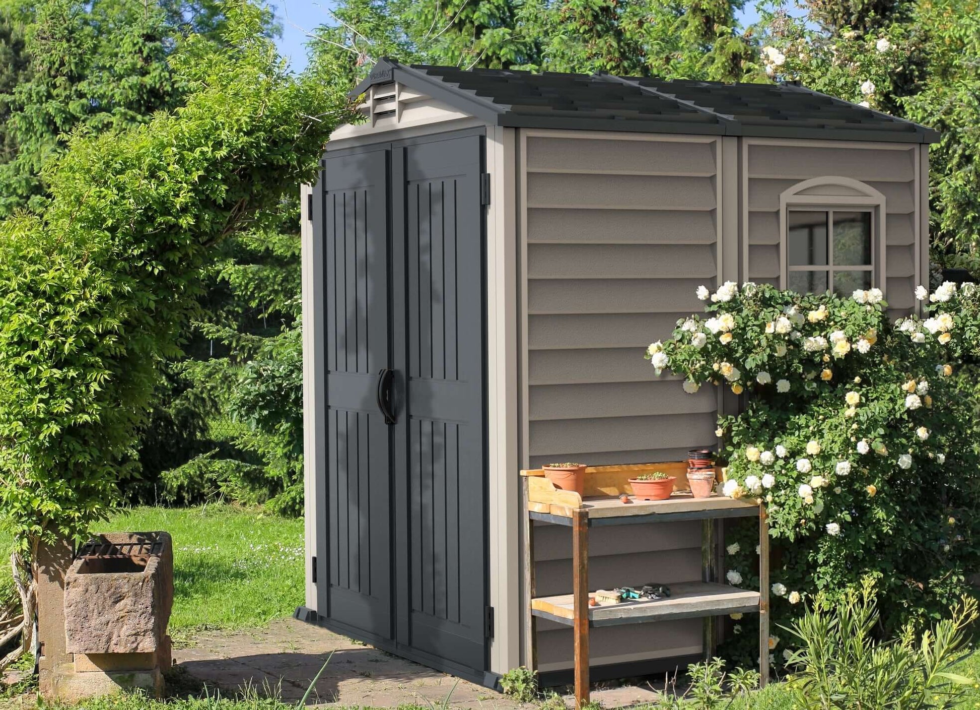 Duramax StoreMate PLUS 6x6 vinyl shed with floor, offering style, security, and fire-retardant vinyl construction against a garden backdrop.