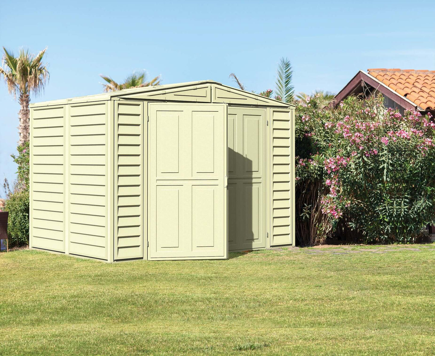 Duramax 8x6 DuraMate Vinyl Shed with Foundation in a garden setting, showcasing durable all-weather design for storage.
